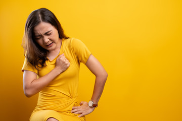 Woman has chest pain isolated over yellow background