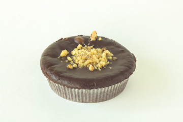 isolated round brown chocolate brownie cupcake in a paper basket sprinkled with walnuts on a white background close-up