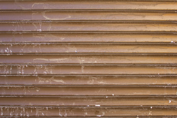 old dirty brown yellow gray metallic blinds with white spots of paint. horizontal lines. rough surface texture