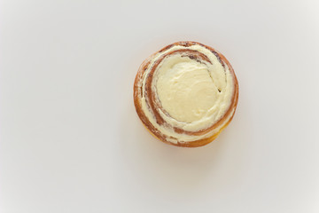 yellow brown round isolated cinnamon cinnabon cream cake close up on white background, top view