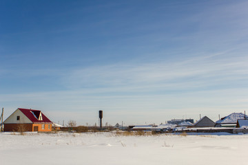water tower and modern village houses under a blue sky with white clouds in winter