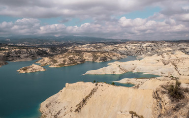 Lake on desser like mountain with eroded rocks with blue cloudy sky