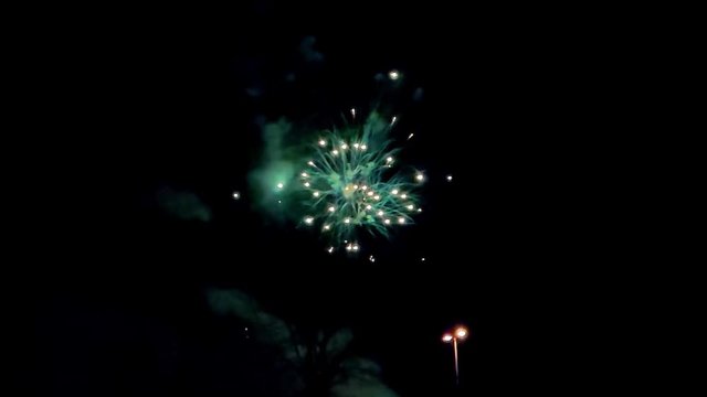 Colourful fire cracker during the festive season in slowmotion in a dark sky with white cloud in a city