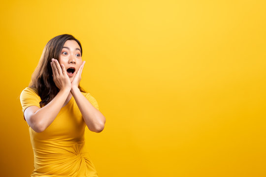 Portrait of excited woman isolated over yellow background