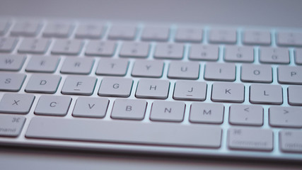 A close-up of a white computer keyboard on a white desk.