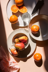 Pears and oranges with  art shadows on a color backround. Artistic healthy breakfast on a table. Still life real life style.