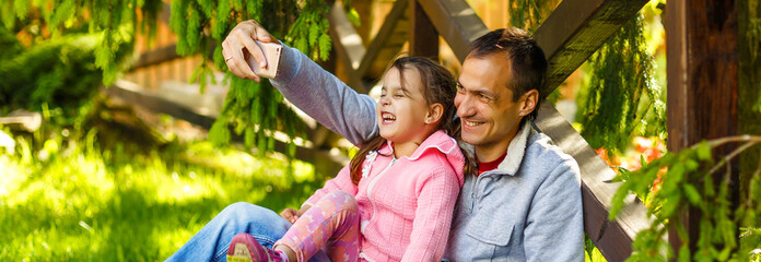 Fototapeta premium Dad and daughter doing selfie in park