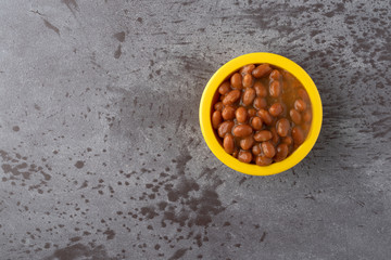 Bowl of baked beans with bacon in a tomato sauce on a gray background top view