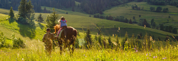 Dad teaches his daughter to ride a horse. Lesson with Riding Instructor. mountain in the background