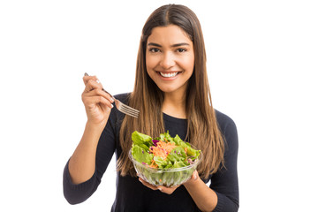 Cute Hispanic woman eating a salad in a studio