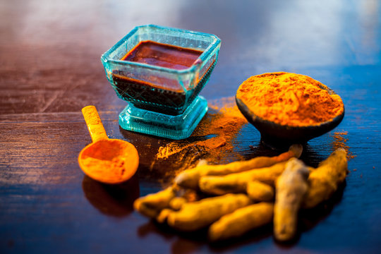 Tamarind or imli or amli in a clay bowl along with its roasted seeds on wooden surface with turmeric or haldi in a clay bowl used for treating acne and pimple.