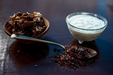 Tamarind or imli or amli in a clay bowl along with raw curd or yogurt in transparent glass bowl on wooden surface used in spa for various skin care treatments.