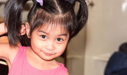 a cute female asian toddler child looking at the camera with cute smile and big brown eyes