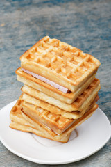 Stack of Viennese waffles on wooden background. Waffles on a white plate, wooden rough blue background.