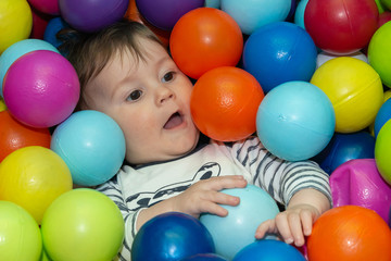 Fototapeta na wymiar The baby boy is playing with color balls