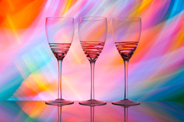 Three wine glasses in a row with colorful light painting behind