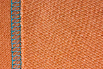 Fototapeta premium Empty orange knitted fabric with decorative elements. Knit texture with stitching. Coral background for wallpaper and other elements of your design.