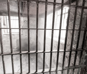 Looking through the bars of a jail cell with mist or fog streaming from a window