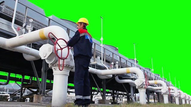 worker closes ball valve on cooling installations at gas compressor station, with alpha channel