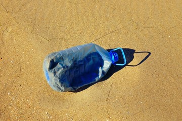 Discarded plastic bottle on a sandy beach.