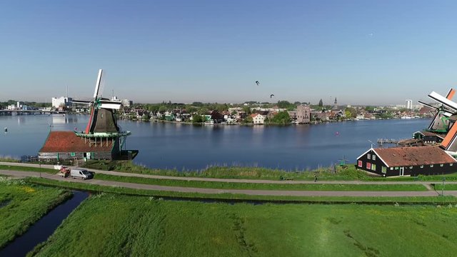 Aerial drone view 4K footage of historic windmills of Zaanse Schans, Zaandam near Zaandijk and Amsterdam Netherlands.  Sunny day in the spring or summer, morning sun. Ducks are flying, people biking