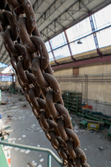Rusty industrial chain with empty workshop space in background
