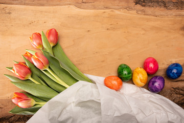 Bunte Blumen und gefärbte Ostereier auf einem Holzbrett