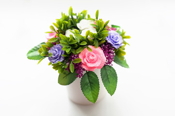 Artificial rose flowers in white vase on white background.