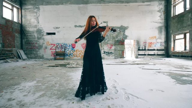 Lady is wearing a dress and playing the violin in a stranded room