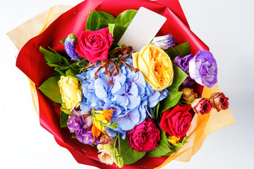 Photo from above bouquet of multi-colored roses with card on empty background