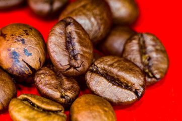 Brown roasted coffee beans on red background, close up, macro