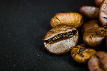 Brown roasted coffee beans on black background, close up, macro