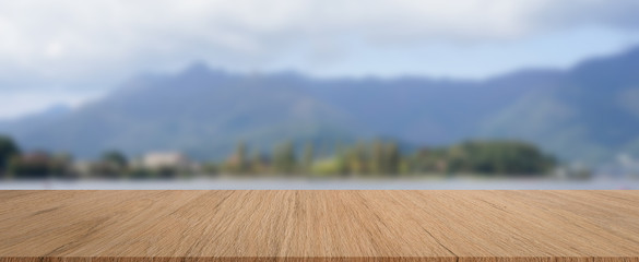 abstract blur viewpoint of natural park ,forest,lake and mountain with brown wood perspective table for show,promote,ads product or content on display concept