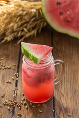 Fresh watermelon smoothie in the mason jar and wheat spike on wooden table