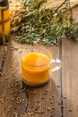 Sea buckthorn tea in cup and wheat spikes on wooden table