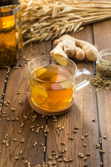 Cup of ginger tea with lemon and wheat spike on wooden table