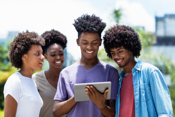 Group of african american young adults posting message with digital tablet