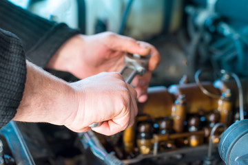Auto mechanic working on car engine in mechanics garage. Repair service. Close-up.