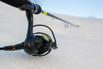 Fishing gear on snow-covered riverbank. Fishing for spinning in the spring.