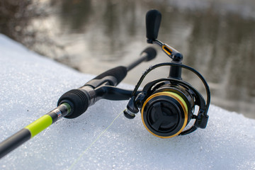 Fishing gear on snow-covered riverbank. Fishing for spinning in the spring.