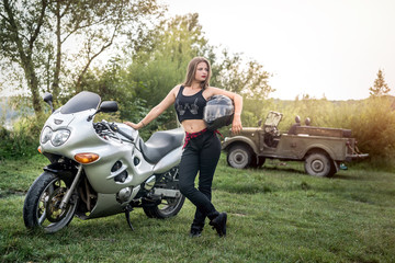 Fototapeta na wymiar Woman with helmet in her hand, stand near motorcycle