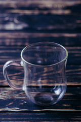Empty glass cup on the dark wooden table and black background
