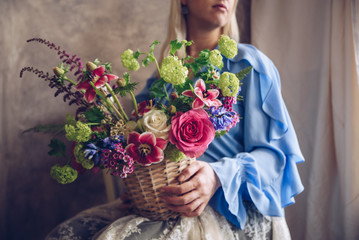 Young woman holding basket with flowers. Vintage, romantic concept.