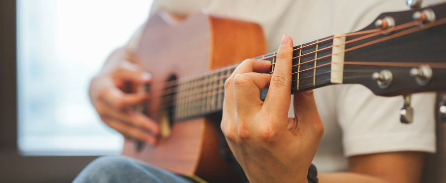 Close up young asian teenager boy open laptop for search song and playing classical guitar for practice  in room , millennial lifestyle concept