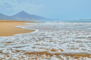 Wonderful view on the shore of the beach of Cofete with waves on the shore in the background in Fuerteventura, Canary Islands, Spain