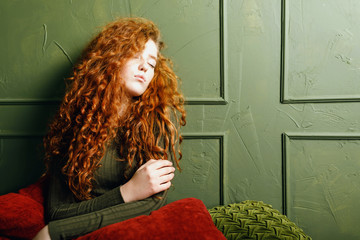  urly ginger girl relaxing at the sofa around the pillows in the green interior