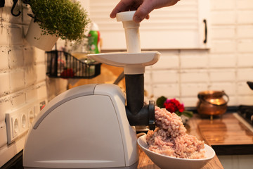 cooking minced meat in an electric meat grinder on the kitchen table