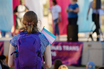 Woman with Backpack and Trans Support Flag at Rally - obrazy, fototapety, plakaty