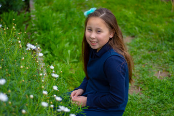 Naklejka na ściany i meble Smiling little latina girl in garden picking flowers