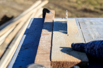 saw blade. car saws wood. there is a blackboard in the background. working hand